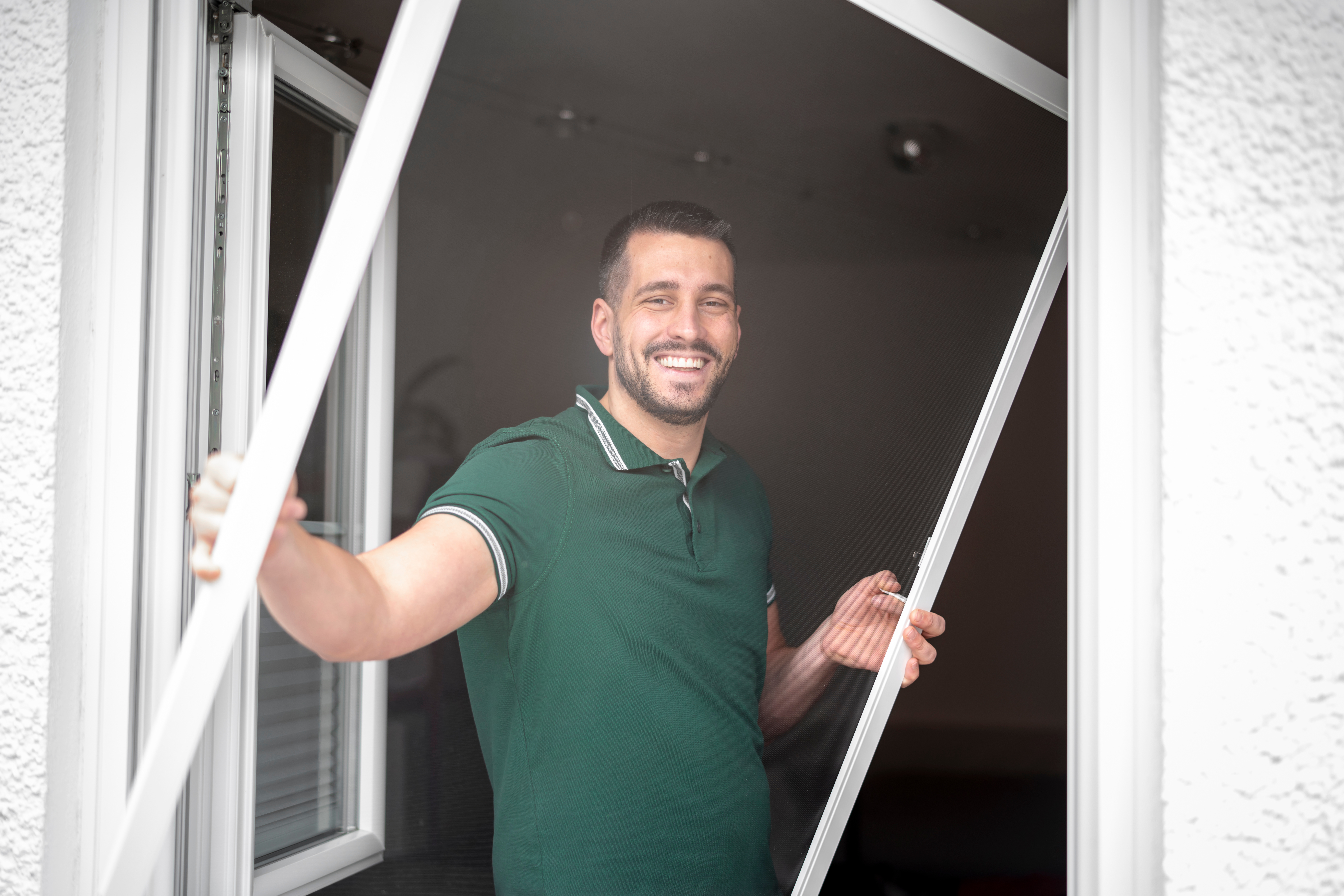 freundlicher Handwerker montiert Insektenschutzgitter bei einem