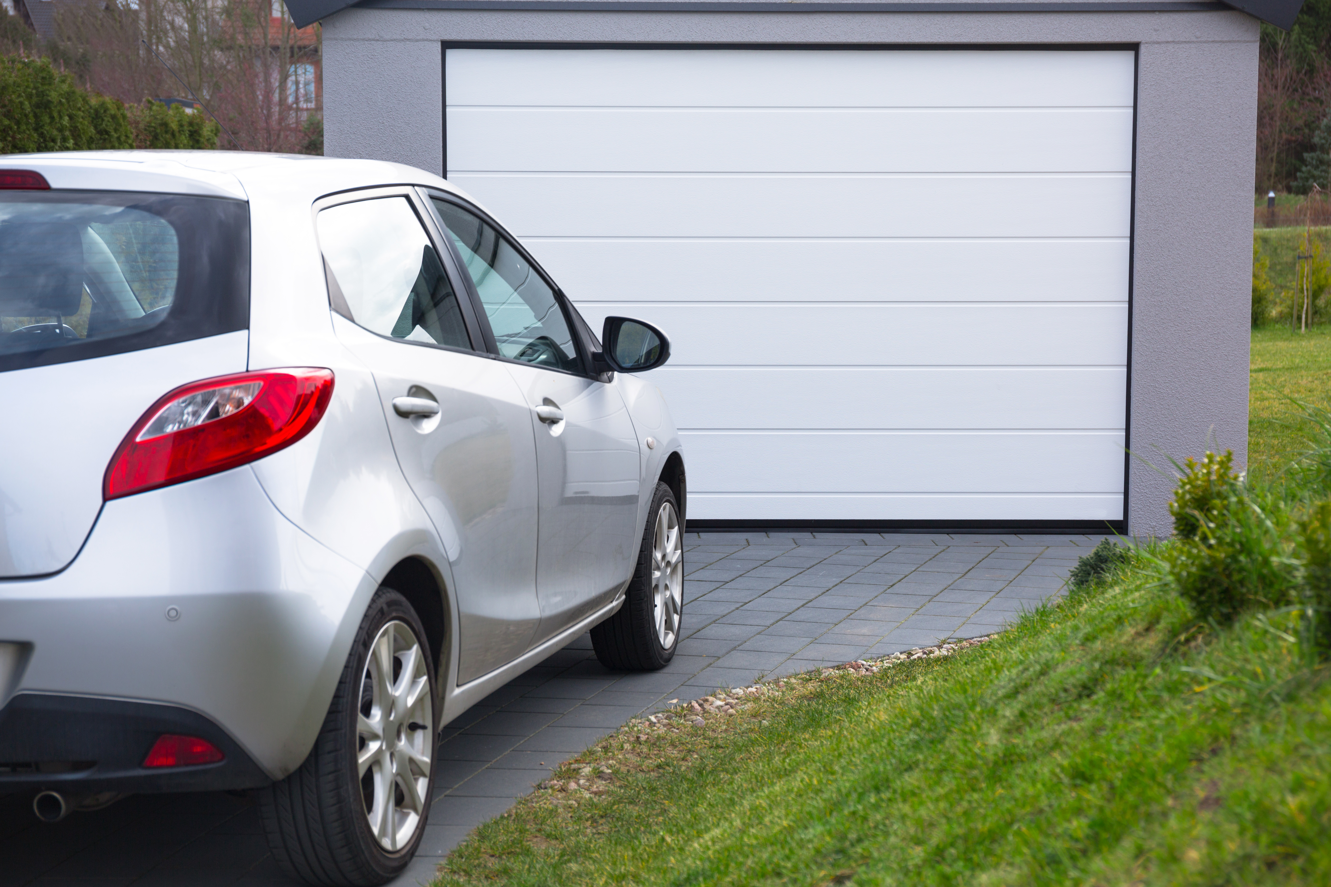 Free-standing garage in the garden with a car parked in front of